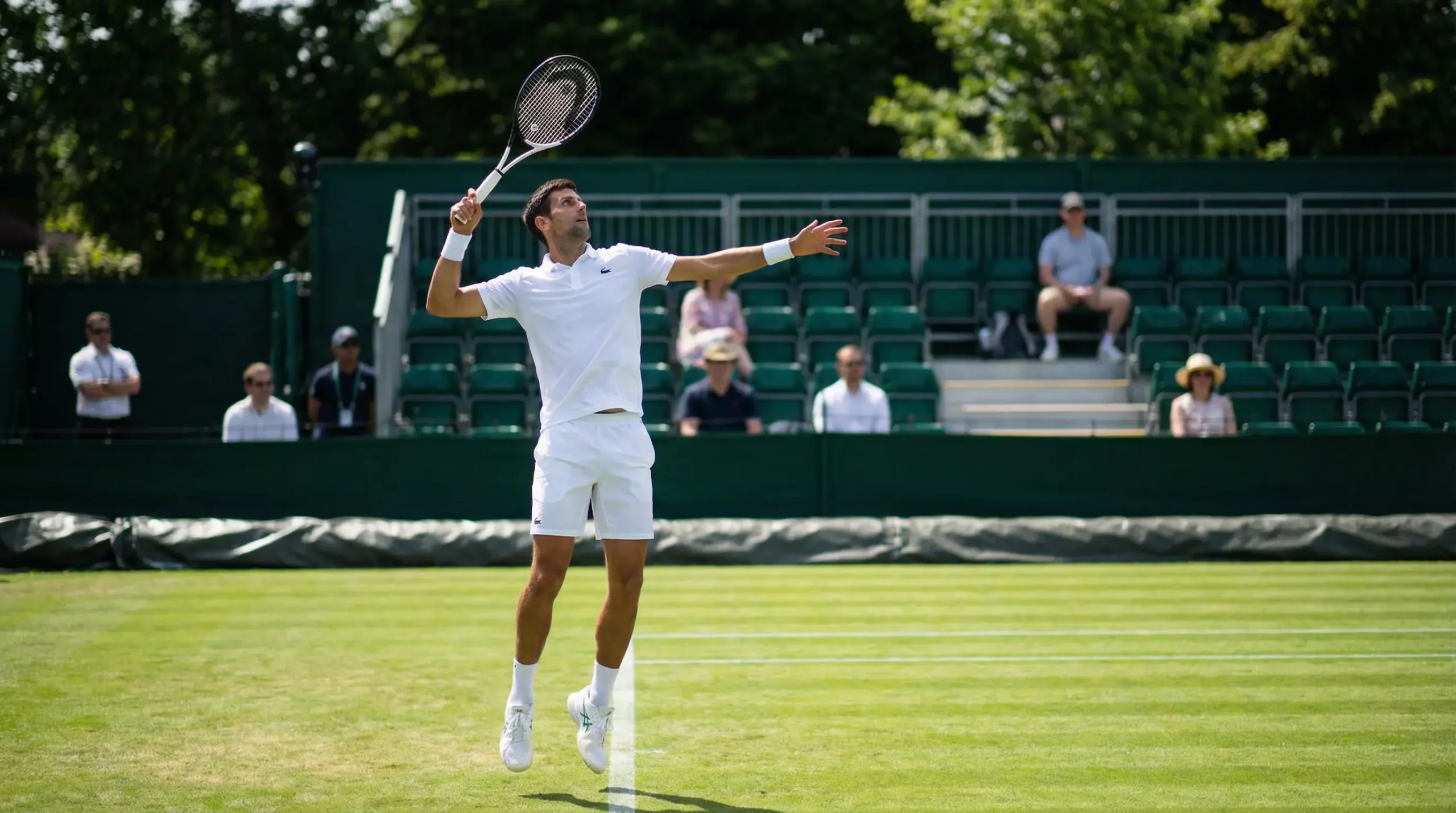 Tennisspieler beim Aufschlag auf einem gepflegten Rasenplatz waehrend eines Vorbereitungsturniers